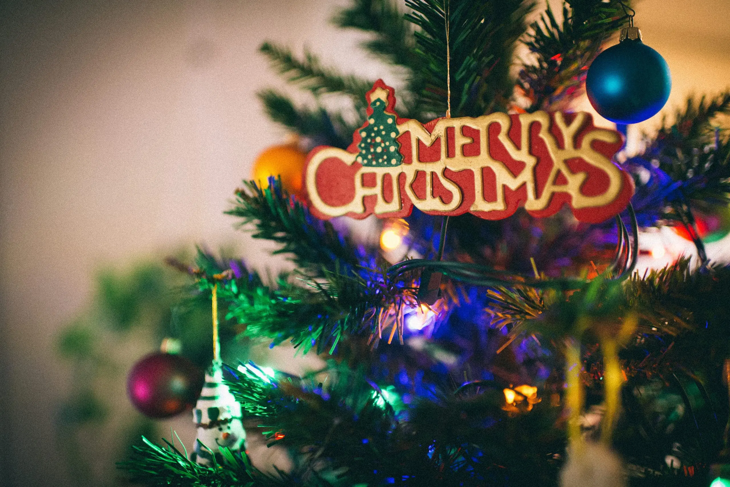 a christmas tree with ornaments and a sign