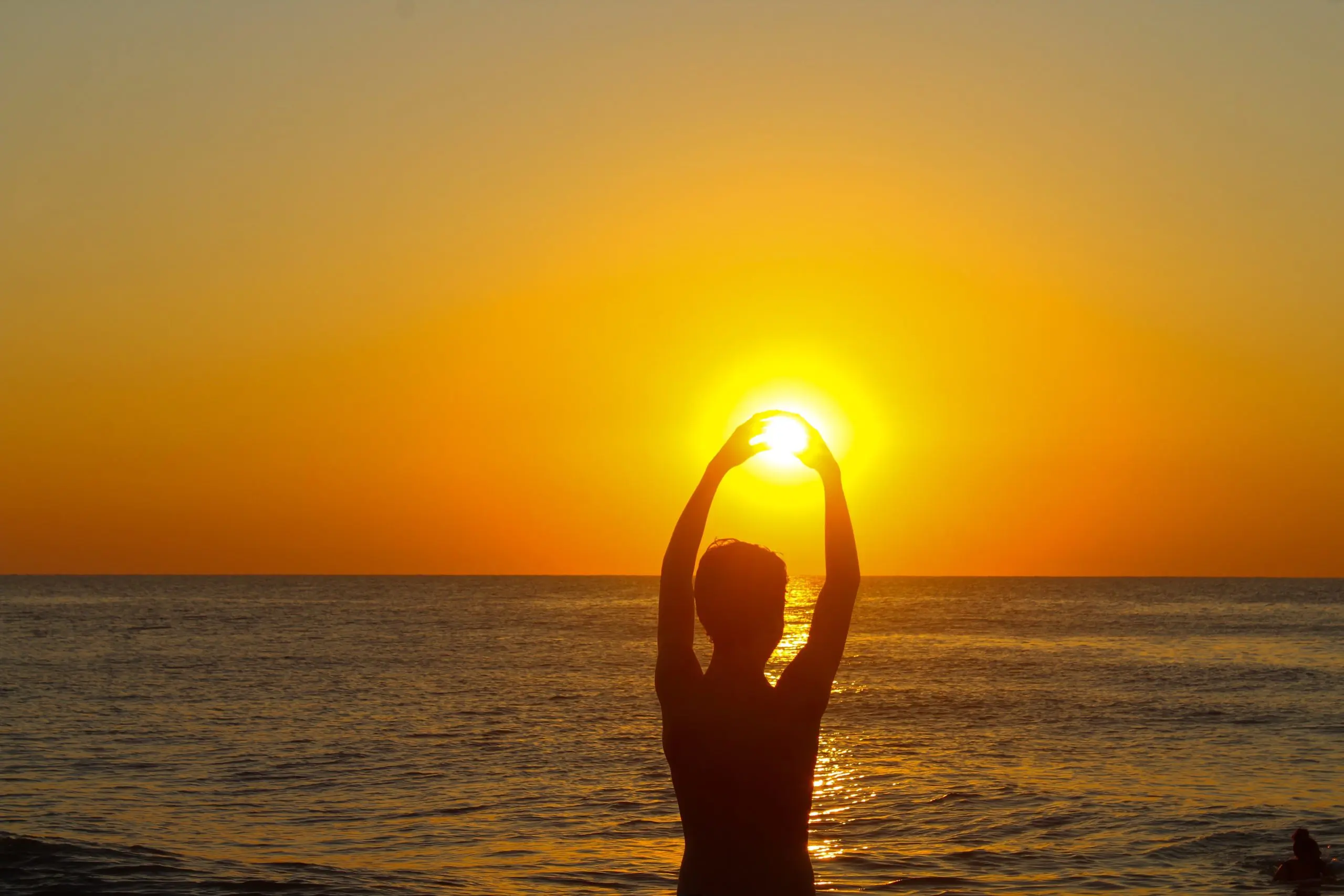 a person holding the sun above the water