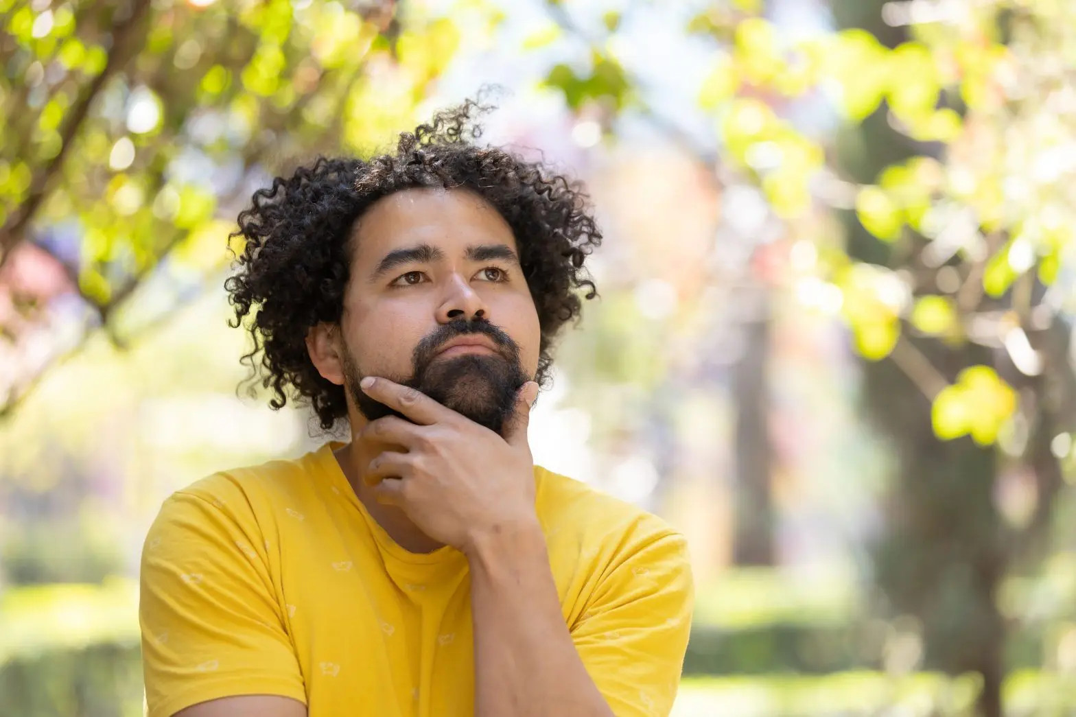 a man with curly hair and a beard in a yellow shirt