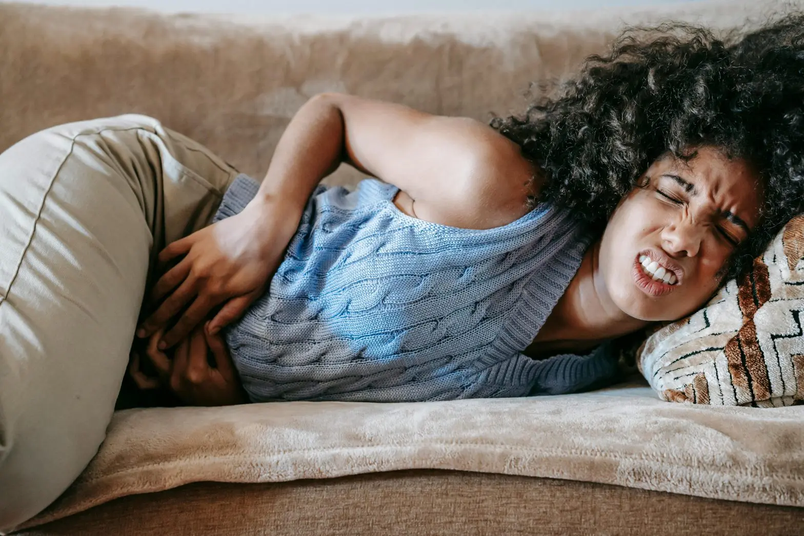 A woman laying on the couch with painful urination after drinking alcohol.