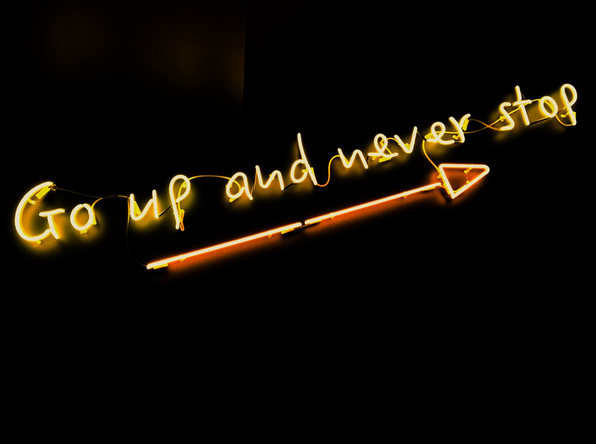 neon sign that reads "Go up and never stop" in reference to addiction recovery