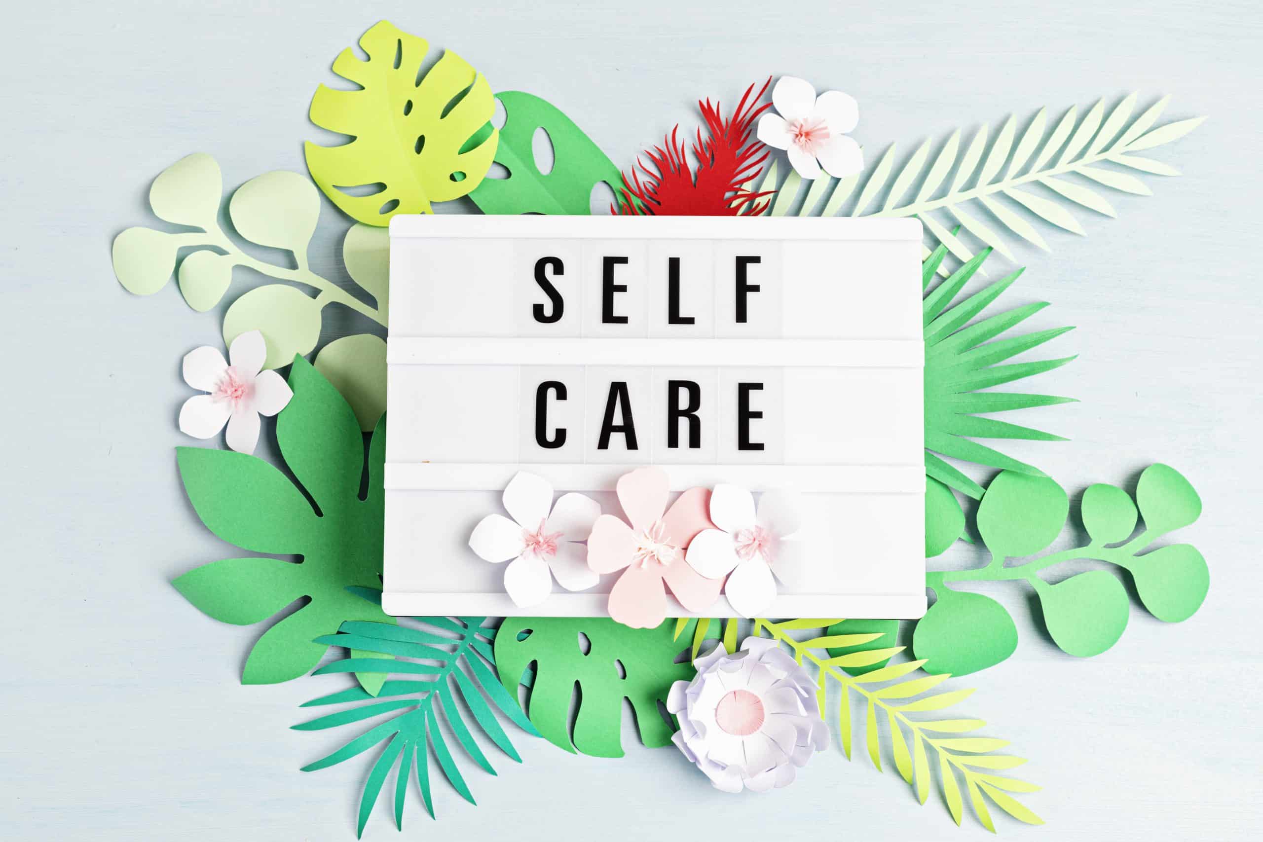 lightbox with the words "self care" surrounded by flowers for National Self Care Day